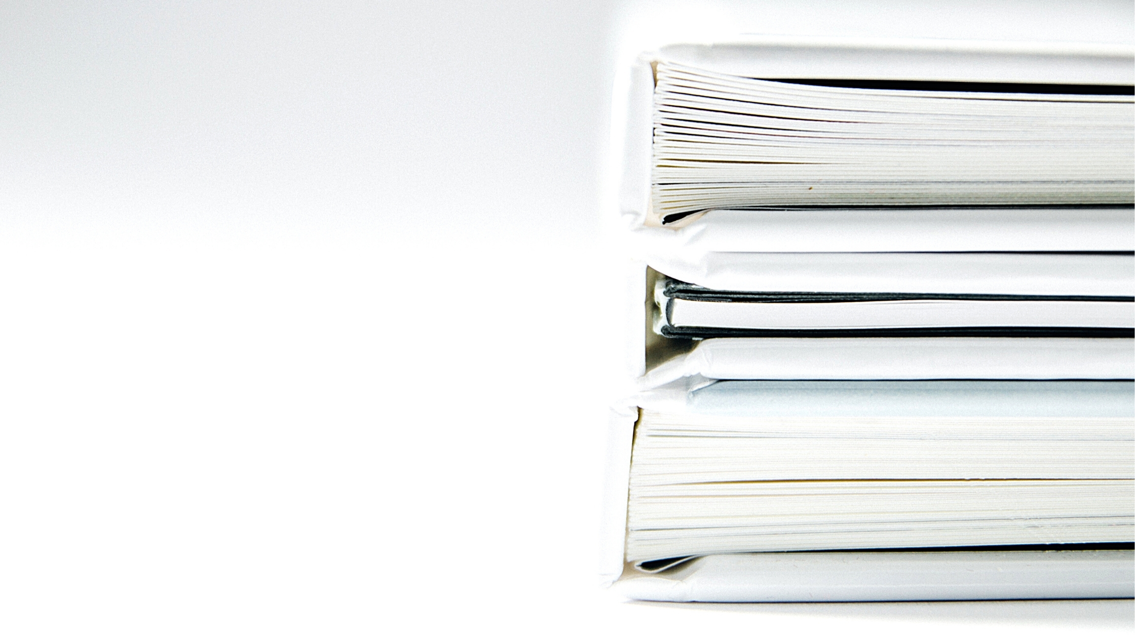 Pile de classeurs et documents papier empilés sur un bureau blanc, vue rapprochée